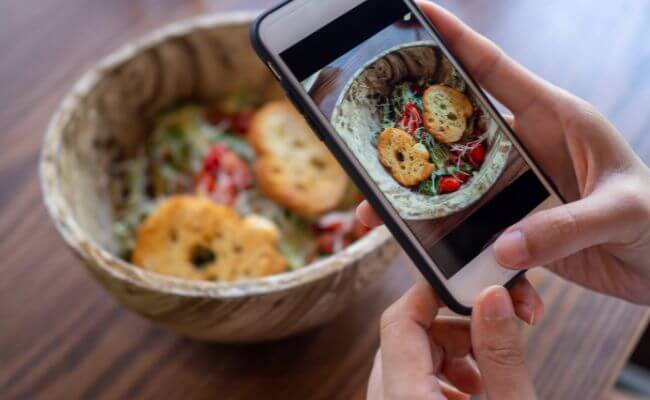 Pessoa fotografando prato de comida, utilizando Instagram para monetizar seu conteúdo culinário