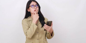 Foto de uma mulher pensativa segurando um smartphone, representando um guia rápido sobre como ver o histórico do Instagram em 2024.