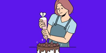 Ilustração de uma confeiteira sorridente com cabelo curto castanho, vestindo avental azul. Ela está decorando um bolo de chocolate com cobertura branca e detalhes de creme rosa, usando um saco de confeitar. O fundo é roxo sólido.