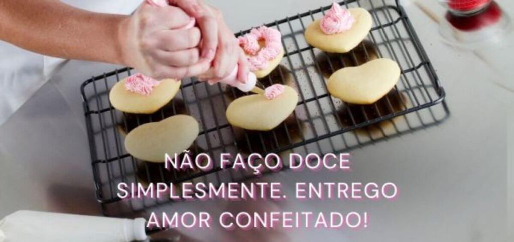 Imagem de uma pessoa decorando biscoitos em forma de coração com glacê rosa, com a frase 'Não faço doce simplesmente. Entrego amor confeitado!