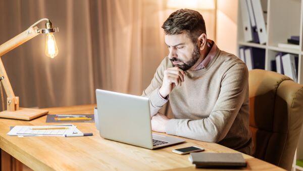 Um homem de negócios trabalhando à noite em seu laptop, concentrado em seu trabalho.