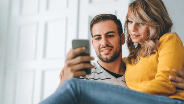 Casal olhando para o celular, representando conectividade, interação digital e procurando legenda para foto masculina.