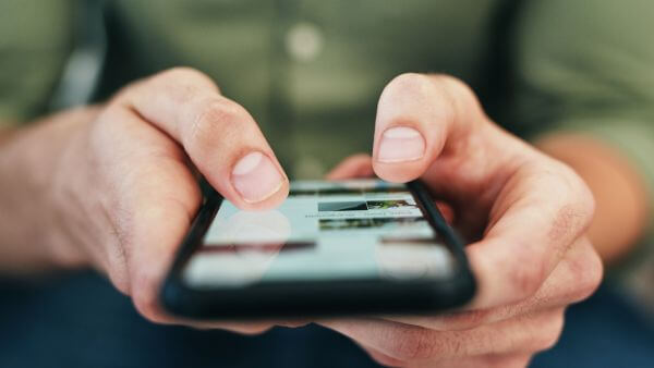 Mãos segurando celular durante a navegação na internet.