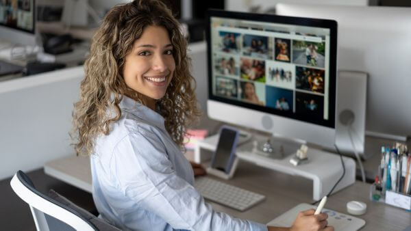 Mulher sorrindo enquanto trabalha no computador.