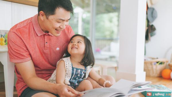 Pai lendo um livro para sua filha sorridente, compartilhando um momento de aprendizado e diversão. Bio para instagram infantil feminino. 

