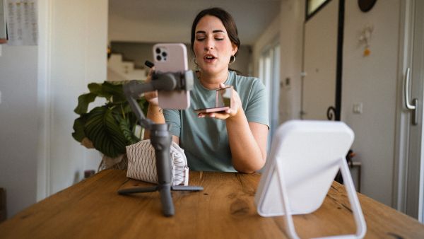 Mulher criando conteúdo digital gravando um vídeo com smartphone em casa.