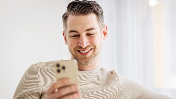 Homem sorridente usando um smartphone, simbolizando a escolha de paletas de cores diretamente no aplicativo do Instagram.